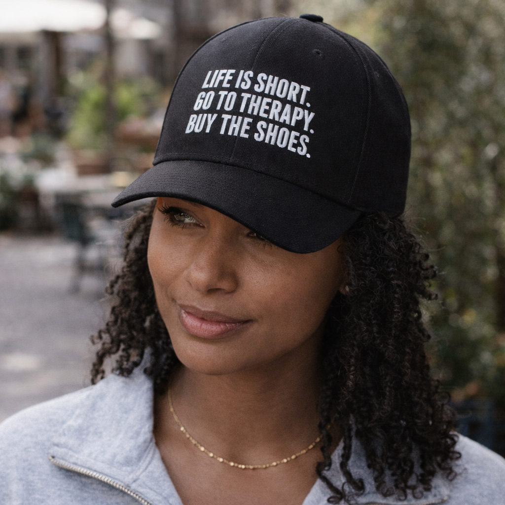 Woman wearing a black cap with text, standing outdoors.